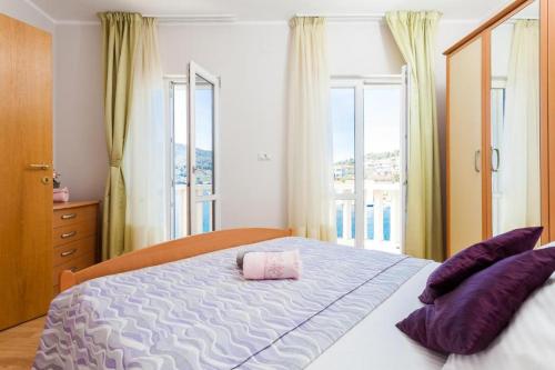 尼亚卢卡Apartments Dea Caeli的一间卧室配有一张带紫色枕头的床和窗户。