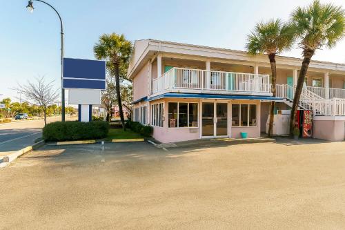 默特尔比奇OYO Hotel Myrtle Beach Kings Hwy的前面有棕榈树的粉红色建筑