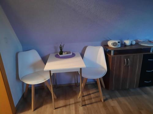GarzFerienwohnung Garz的客房内的2把白色椅子和1张桌子