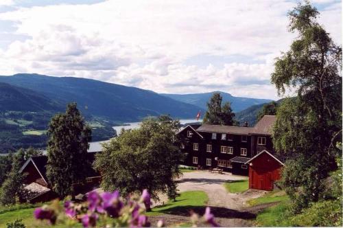 TrettenGlomstad Gjestehus的一座大建筑,位于山丘上,背景是群山