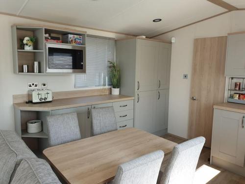 坎伯利The Sea Breeze - 8 Berth Premium Caravan in Camber Sands的厨房配有木桌和椅子