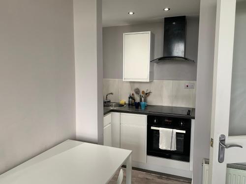 拉格斯Seaview one bedroom apartment in centre of Largs的厨房配有白色橱柜和黑烤箱。