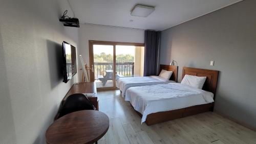 西归浦市海树之家度假屋的酒店客房带两张床、一张桌子和一张桌子。