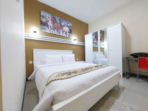 三宝垄Rons City Hotel near Simpang Lima Semarang Mitra RedDoorz的卧室配有一张白色大床和一张书桌