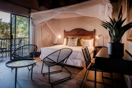 卡萨内Chobe Marina Lodge的一间卧室配有一张床铺和椅子,设有一个阳台