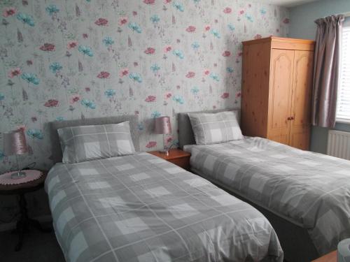 彭里斯Daleholme的卧室内的两张床,配有花卉壁纸