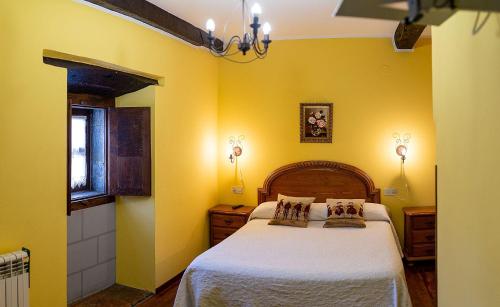 AvínLa Corrolada的一间卧室拥有黄色的墙壁,床上铺有白色的床单。