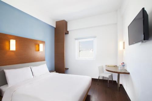 哥伦打洛省哥伦打洛爱玛瑞丝酒店的一间卧室配有一张床、一张桌子和一台电视。