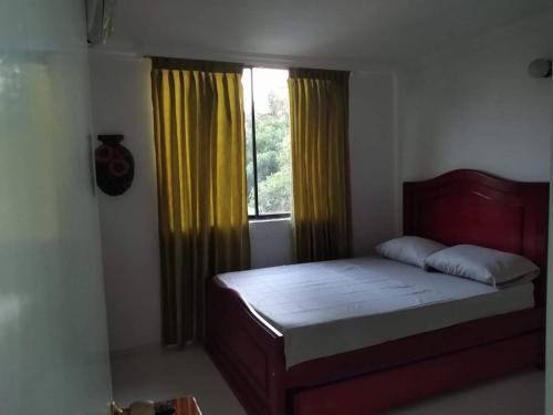 圣玛尔塔Acogedor apartamento a 15 metros del mar的一间卧室设有床和黄色窗帘的窗户