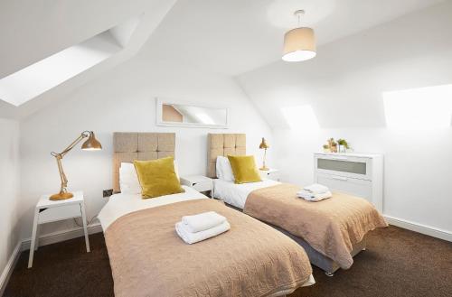 QueensburyAmbler Thorn Lodge的配有白色墙壁和黄色枕头的客房内的两张床