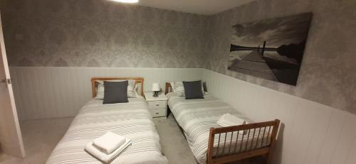BescotLadbury House in Walsall, Near the M6 and near Walsall Manor Hospital, with free parking and easy access to Birmingham city centre, perfect for contractors and families, only 20 minutes from NEC and Birmingham airport的卧室内配有两张单人床,墙上挂着一幅画