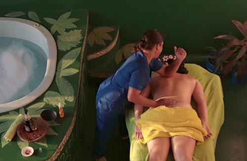 莱蒂西亚Eco Hotel El Refugio de La Floresta的女人给男人穿镜子洗澡