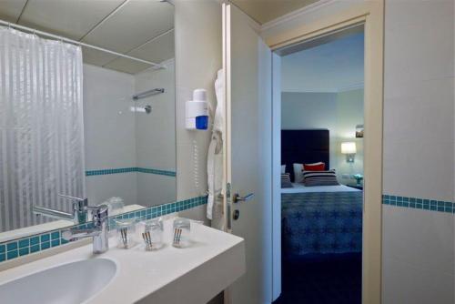特拉维夫大都会酒店的一间带水槽和镜子的浴室以及一张床