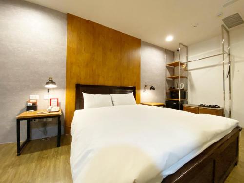 台中市台中欧菲旅店的卧室配有一张白色大床和一张书桌