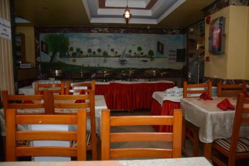 卢克索New Saint Catherine Hotel的餐厅设有桌椅,墙上挂有绘画作品