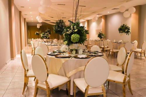 戴维太阳门酒店的宴会厅配有长桌子和白色椅子