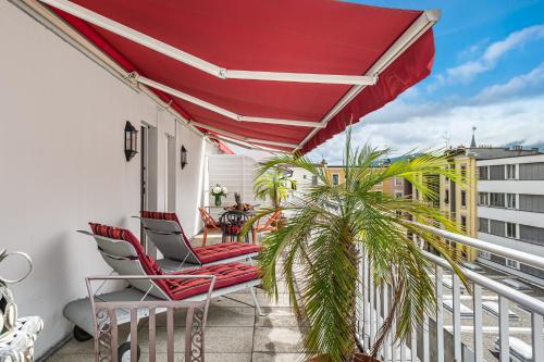 日内瓦吉卜林玛诺特酒店的阳台配有两把椅子和一把红色遮阳伞
