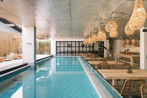 清迈Glory Wabi Sabi Hotel清迈古城荣耀侘寂酒店的一个带桌椅的房间的游泳池