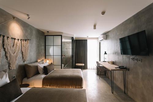清迈Glory Wabi Sabi Hotel清迈古城荣耀侘寂酒店的一间卧室配有一张床、一张书桌和一台电视