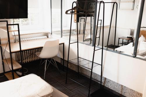 肯普滕Unterkunft KemptenCityHost的客房配有书桌和白色椅子。