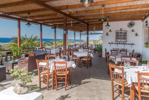 Agia Irini Milos加里尼酒店的餐厅设有桌椅,背景为大海