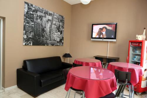 米兰比可卡酒店的客厅设有两张桌子、一张沙发和一台电视机