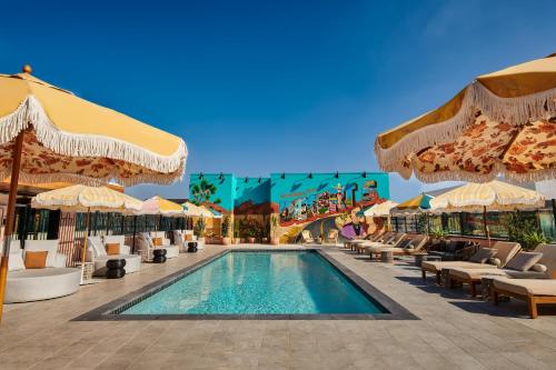 洛杉矶tommie Hollywood, part of Jdv by Hyatt的度假村的游泳池,配有椅子和遮阳伞