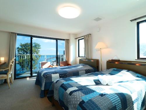 热海Izu Kansya的带阳台的酒店客房内的两张床