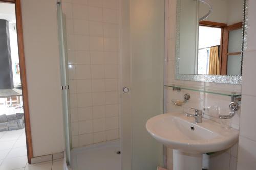 塔那那利佛Aina Hôtel的浴室配有盥洗盆和带镜子的淋浴