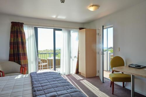 凯库拉凯库拉品质套房汽车旅馆的一间带一张床和一张书桌的卧室以及一个阳台