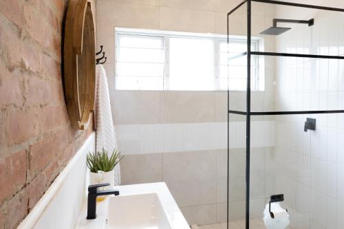 德班Peaceful Modern Home with Private Garden in Durban North的一间带水槽和玻璃淋浴的浴室