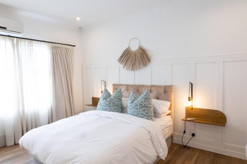 德班Peaceful Modern Home with Private Garden in Durban North的卧室配有带蓝色枕头的大型白色床