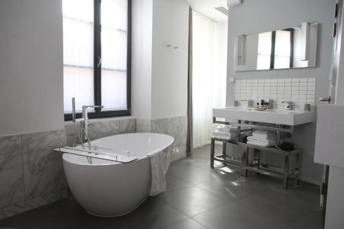 科尔马Hôtel Quatorze的白色的浴室设有浴缸和水槽。