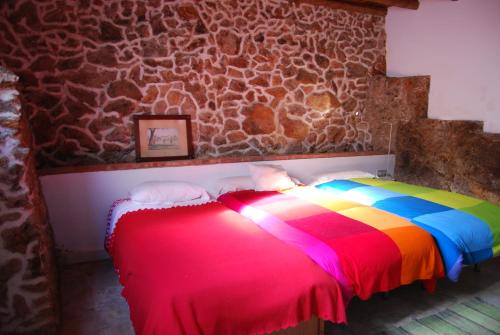ValdelarcoCASA DE DOÑA MARIA VALDELARCO的一张色彩缤纷的床,位于一个石墙房间内