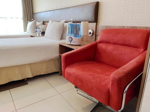 巴西利亚阿托斯布尔考普拉斯行政酒店的酒店客房,配有一张床和一张红色椅子