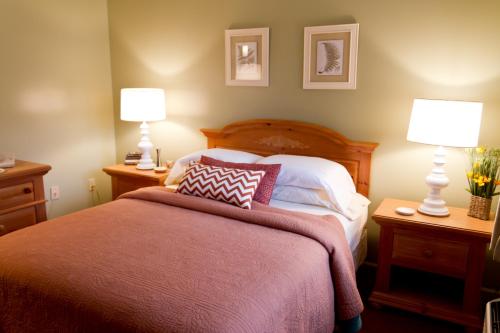拉丁顿Summers Inn Ludington - Adults Only的一间卧室配有一张大床,桌子上放着两盏灯