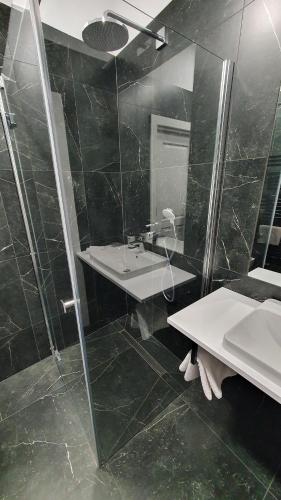 耶维克Apartamenty SIENKIEWICZA 8的黑色瓷砖浴室设有水槽和淋浴