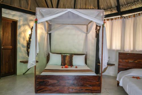 帕洛米诺Sublime by Playa la Roca EcoHotel的卧室配有带白色窗帘的天蓬床