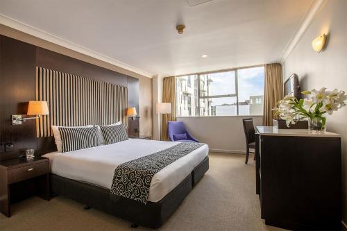惠灵顿美居惠灵顿贝尔塔斯曼酒店的酒店客房设有一张大床、一张桌子和一张桌子。