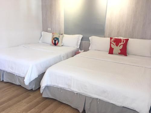 垦丁大街In 垦丁的配有白色床单和红色枕头的客房内的两张床