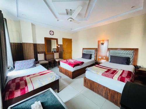 拉希迈尔汗Plaza Inn Hotel的酒店客房,配有两张床和椅子