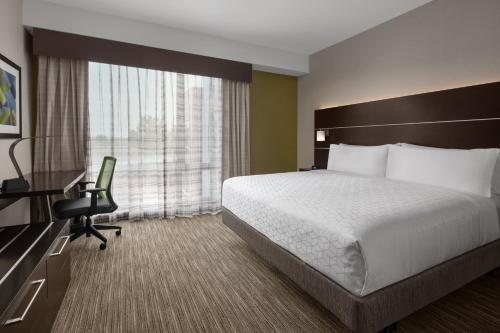 皇后区Holiday Inn Express & Suites Woodside LaGuardia Airport的酒店客房配有一张床、一张桌子和一把椅子。