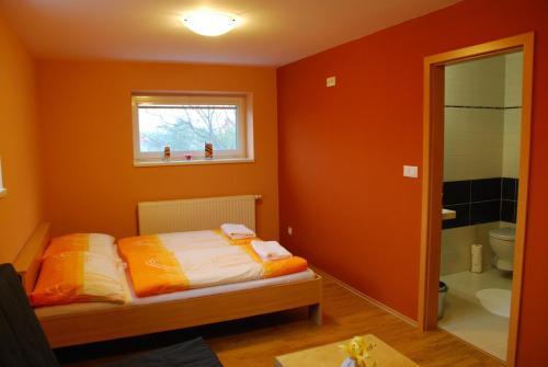 捷伊科维采维纳斯维诺沃提尼旅馆的一间卧室拥有橙色的墙壁、一张床和窗户