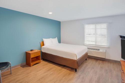 哈灵根WoodSpring Suites Harlingen的一间卧室设有一张床和蓝色的墙壁