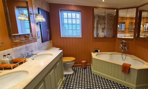 泰恩The Glenmorangie House的一间带两个盥洗盆、浴缸和卫生间的浴室