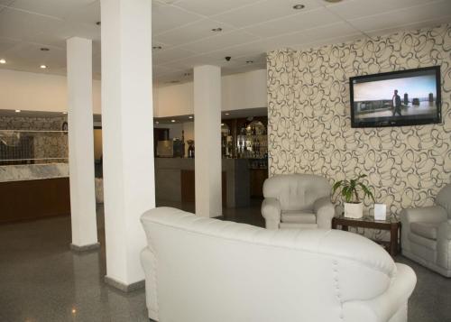 马德普拉塔Gran Hotel Manila的客厅配有两把白色椅子和墙上的电视