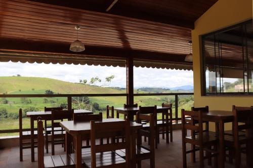 上波苏Pousada Montanhas das Gerais的餐厅设有桌椅和大窗户。