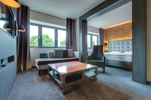 吕贝克吕贝克丽笙公园酒店的客厅配有床、沙发和桌子