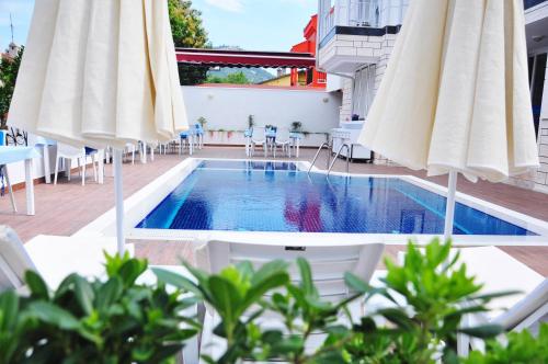 凯麦尔Amsterdam Otel & Suite Apart的一个带白色遮阳伞和桌椅的游泳池