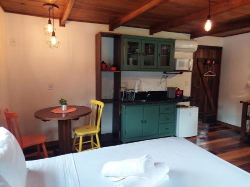 圣博尼法西乌Caminhos da Serra do Tabuleiro - Chalé do Lago的厨房配有绿色橱柜、桌子和床。